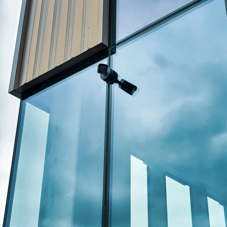 CCTV camera against modern glass office building.