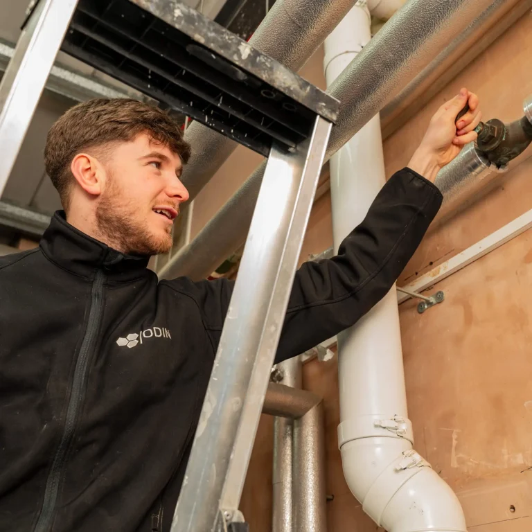 an engineer wearing an Odin uniform turning a dial on a pipe
